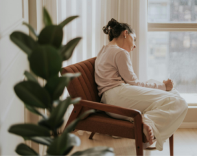 Image of a contemplative woman relaxing by a window.