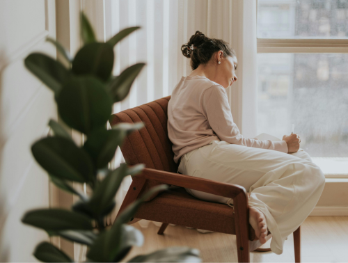 Image of a contemplative woman relaxing by a window.