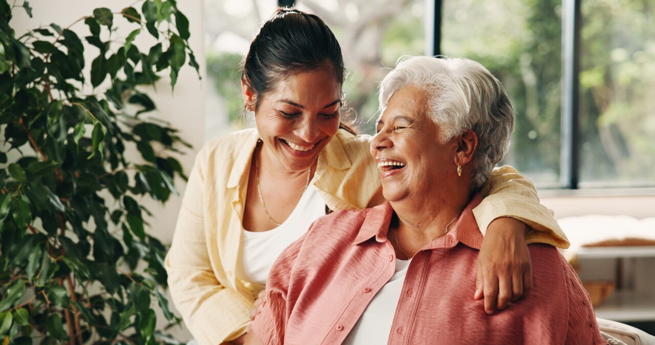 Image of a younger woman with her arm around an older woman, both of them happy and laughing.
