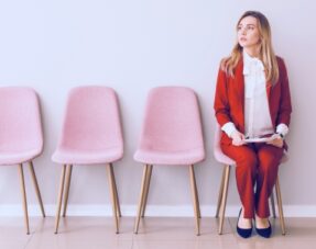 Photo of a woman sat on a chair next to several other empty chairs.