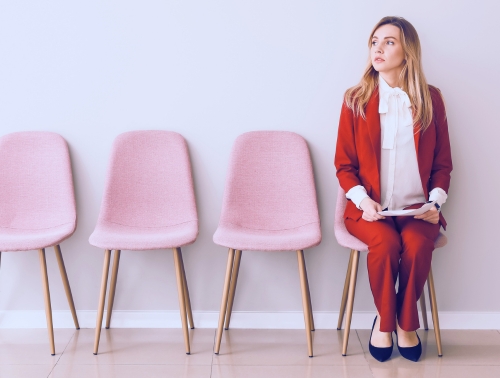 Photo of a woman sat on a chair next to several other empty chairs.